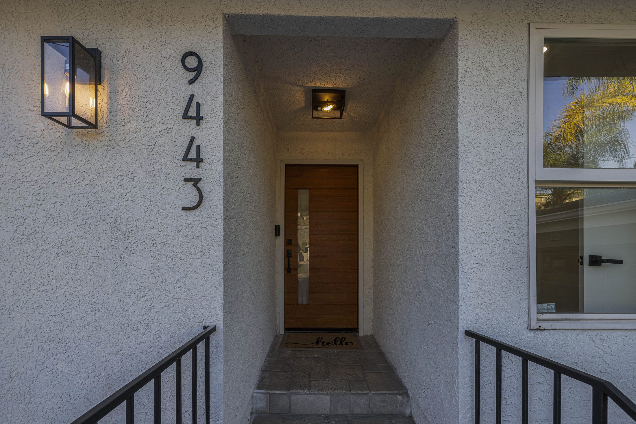 Covered front entry with wood door and house numbers
